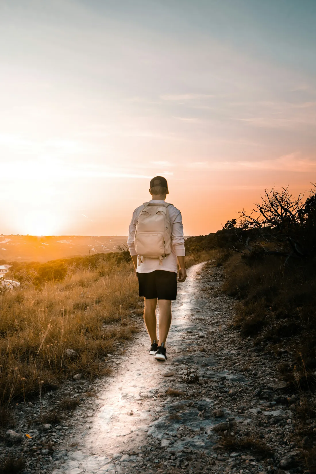 Un homme marche sur un chemin de terre vers le soleil couchant